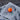 Orange colored course logo golf ball on a gray towel with a blurred wood background